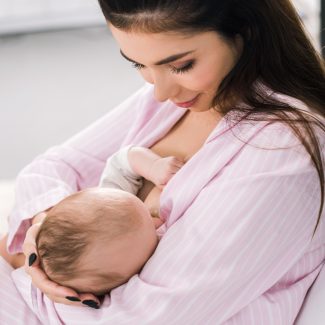 young mother breastfeeding little baby at home